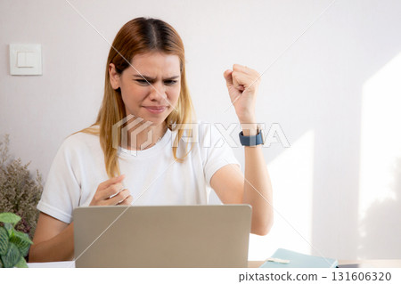 Unhappy young caucasian businesswoman using laptop computer on desk with stress and burnout. 131606320