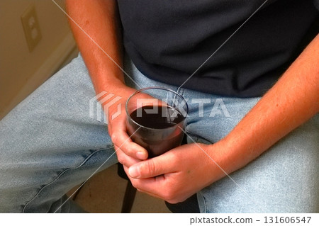 Man holding glass of dark drink 131606547