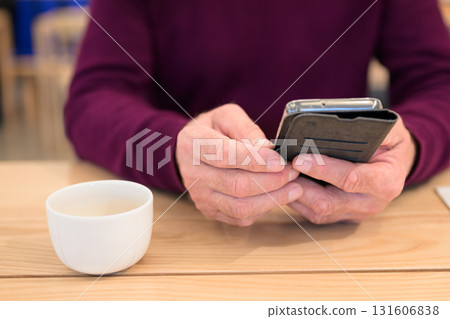 Man using mobile phone at table in cafe. Focus on hands. Man using mobile phone at table in cafe. Focus on hands. 131606838