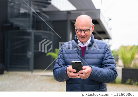 Senior man using his mobile phone in front of a modern building 131606863