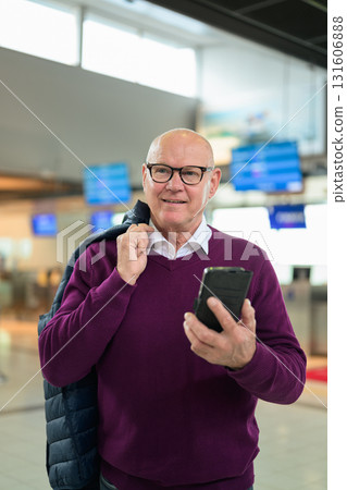 Portrait of happy senior man using mobile phone while standing in airport 131606888