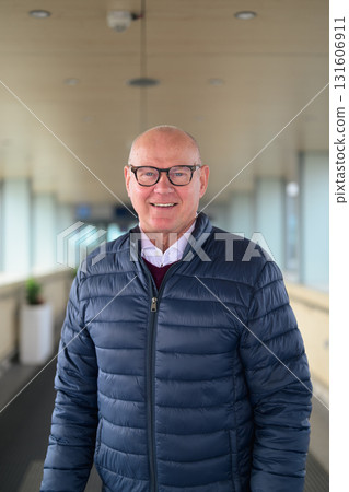 Portrait of a smiling senior Scandinavian man wearing eyeglasses in an airport corridor Portrait of a smiling senior Scandinavian man wearing eyeglasses in an airport corridor 131606911