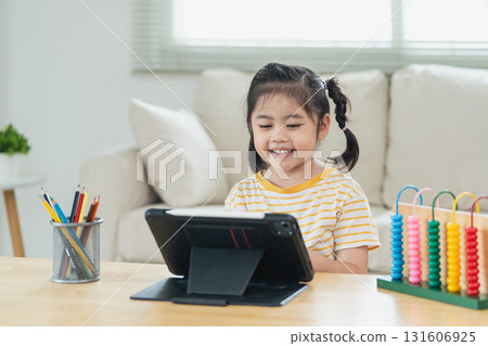 Happy young girl using tablet for education at home with colorful abacus and art supplies in minimalistic living room Happy young girl using tablet for education at home with colorful abacus and art supplies in minimalistic living room 131606925