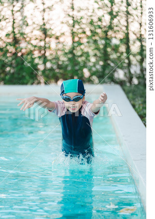 Child in Swim Cap and Goggles Splashing in Pool Water, Capturing Joyful Moment During Summer Swim Lesson in Bright Natural Light Setting 131606933