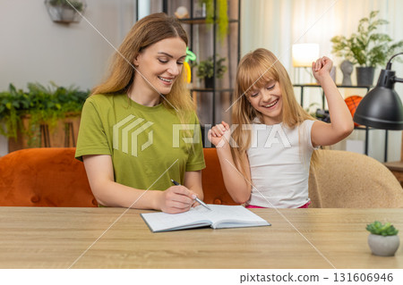 Mother daughter play tic tac toe on paper rounds keep score notebook laugh rematch at table together 131606946