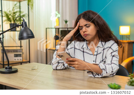Indian woman upset after bad news on smartphone presses button places phone aside unhappy reaction Indian woman upset after bad news on smartphone presses button places phone aside unhappy reaction 131607032