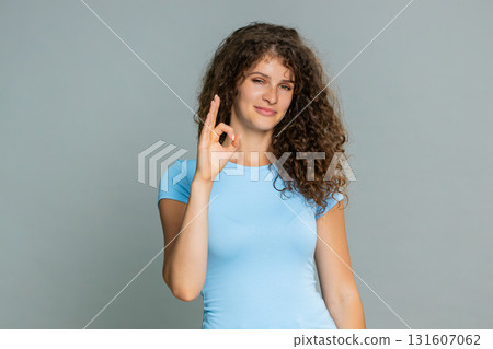 Woman smiling showing OK gesture approval satisfaction positive feedback happy pleased expression Woman smiling showing OK gesture approval satisfaction positive feedback happy pleased expression 131607062