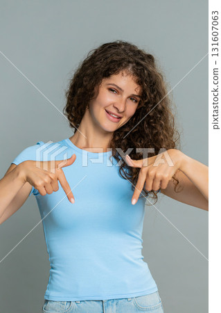Woman smiling pointing downward gesture subscribe call action encouraging follow social media blog Woman smiling pointing downward gesture subscribe call action encouraging follow social media blog 131607063