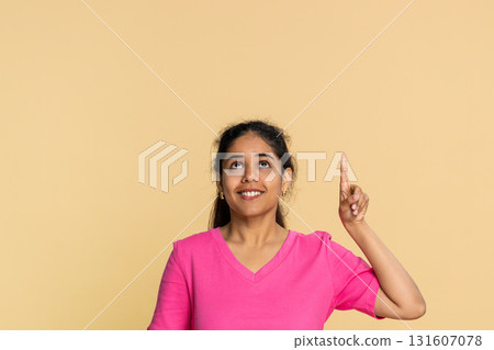 Indian woman seriously pointing finger upwards, indicating important message or announcement above Indian woman seriously pointing finger upwards, indicating important message or announcement above 131607078