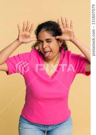 Indian woman playfully sticking out tongue towards camera, expressing joyful teasing personality Indian woman playfully sticking out tongue towards camera, expressing joyful teasing personality 131607079
