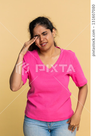 Indian woman emotionally covers face with hands showing sadness, looking sadly through fingers 131607080