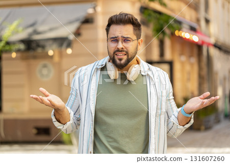 Doubtful sad frustrated young Caucasian man shrugging shoulders dont know answer on city street Doubtful sad frustrated young Caucasian man shrugging shoulders dont know answer on city street 131607260