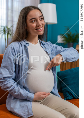 Happy pregnant woman walks her fingers over her large belly expecting baby playing with unborn child 131607269
