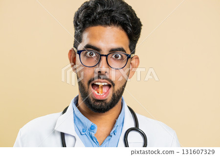 Doctor man puts vitamin D or omega-3 tablet pill into mouth recommends drugs immunization treatment Doctor man puts vitamin D or omega-3 tablet pill into mouth recommends drugs immunization treatment 131607329