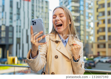Happy businesswoman using smartphone celebrating victory win message news on downtown city street Happy businesswoman using smartphone celebrating victory win message news on downtown city street 131607340