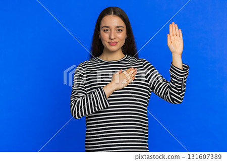 Woman raising hand to take oath, promising to be honest and to tell truth, keeping hand on chest Woman raising hand to take oath, promising to be honest and to tell truth, keeping hand on chest 131607389