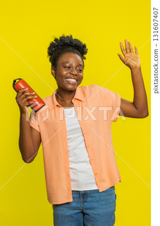 African American woman dancing with red portable speaker, energetic moves, enjoying rhythm of music 131607407