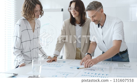 Professional team reviewing financial data, collaborating on working documents, demonstrating team achievements and positive dynamics in the workplace. Business people concept 131607558