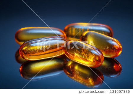Golden gel capsules with omega oil supplements are displayed on reflective surface, showcasing their glossy texture and rich color. image highlights health benefits and appeal of these supplements 131607586
