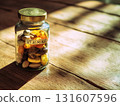 Glass jar filled with various vitamins and supplements sits on wooden table, illuminated by warm sunlight streaming through window, creating cozy and inviting atmosphere 131607596