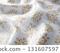White fabric with floral pattern in gold tones, showcasing intricate design details and soft texture. fabric appears elegant and luxurious, suitable for home decor or fashion 131607597