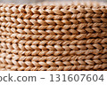 Close up of woven natural fiber basket showcases intricate texture and craftsmanship, highlighting detailed interlacing of fibers. warm tones and organic material evoke sense of rustic charm 131607604