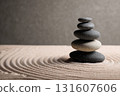 Zen rock stack in sand garden, creating serene and balanced atmosphere. smooth stones are carefully arranged, surrounded by raked sand patterns, symbolizing tranquility 131607606