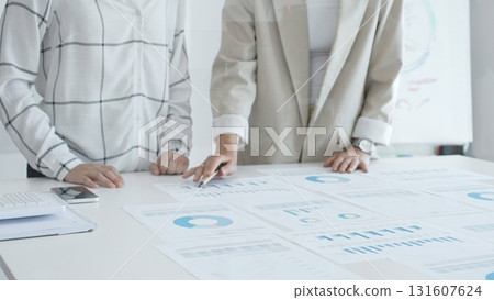 Professional women analyzing financial charts, discussing business strategy in modern light office, in collaborative corporate environment. Business people concept 131607624