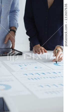 Professional team reviewing financial documents, pointing at charts on desk, collaborating to analyze data and strategize business growth. Business people concept 131607636