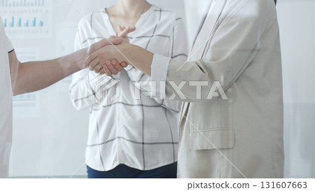Business people shaking hands and clapping after closing deal in contemporary office setting. Handshake concept 131607663