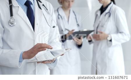 Healthcare professional using a digital tablet for patient data management, doctors collaborating on medical records, modern clinic team focusing on health technology Healthcare professional using a digital tablet for patient data management, doctors collaborating on medical records, modern clinic team focusing on health technology 131607671