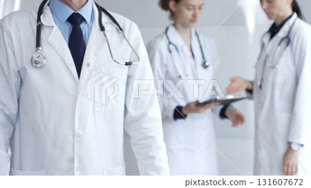Doctors working together in a well-lit hospital environment, demonstrating patient care, professionalism, and strong teamwork in healthcare 131607672
