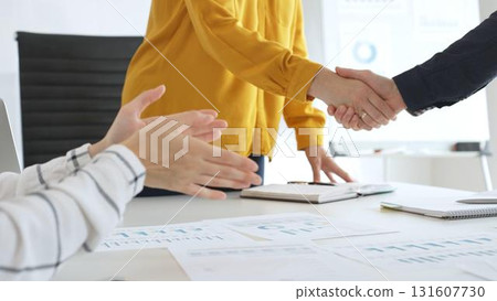 Professional businesspeople shaking hands, confirming partnership agreement in contemporary corporate sunny office. Business handshake 131607730