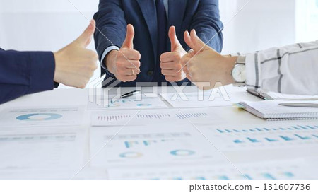 Business team showing thumbs up sign in meeting celebrating success with financial charts, data analysis, sales growth reports, and teamwork achievement in modern office Business team showing thumbs up sign in meeting celebrating success with financial charts, data analysis, sales growth reports, and teamwork achievement in modern office 131607736