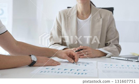 Professional businesspeople collaborating on financial analysis, female executive gesturing toward charts while presenting strategic insights to team members in corporate workspace Professional businesspeople collaborating on financial analysis, female executive gesturing toward charts while presenting strategic insights to team members in corporate workspace 131607751