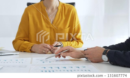 Business professionals gathered around conference table, reviewing financial charts, collaborating on strategic planning and corporate analysis Business professionals gathered around conference table, reviewing financial charts, collaborating on strategic planning and corporate analysis 131607774