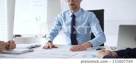 Business professional presenting financial strategy during corporate meeting with colleagues, analyzing charts and discussing data for growth and success planning 131607784