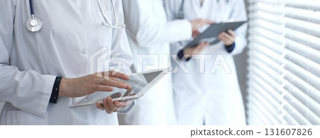 Medical professional using a digital tablet for patient care and data management, collaborating with doctors and healthcare workers in a modern clinic or hospital setting Medical professional using a digital tablet for patient care and data management, collaborating with doctors and healthcare workers in a modern clinic or hospital setting 131607826