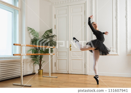 Young ballerina in tutu skirt dancing practicing ballet positions in dance class. Young classical dancer woman in dance studio. Ballet class training. Performer girl rehearsing dance in ballet school Young ballerina in tutu skirt dancing practicing ballet positions in dance class. Young classical dancer woman in dance studio. Ballet class training. Performer girl rehearsing dance in ballet school 131607941