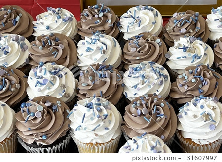 兩個美味的紙杯蛋糕,上面鋪滿了新鮮奶油 兩個美味的紙杯蛋糕,上面鋪滿了新鮮奶油 131607997