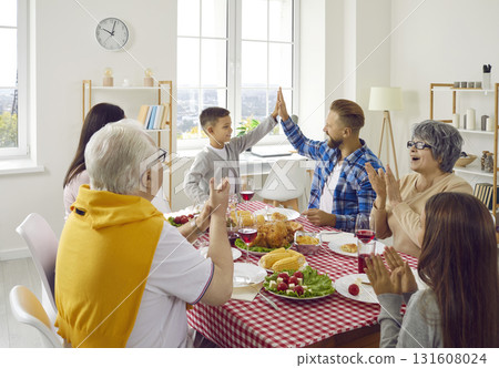 Big family congratulates father dad and clapping hands during family dinner in living room. 131608024