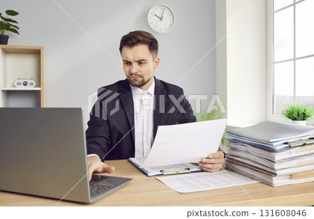 Young business man working at the desk with a pile of documents on his workplace at office. 131608046