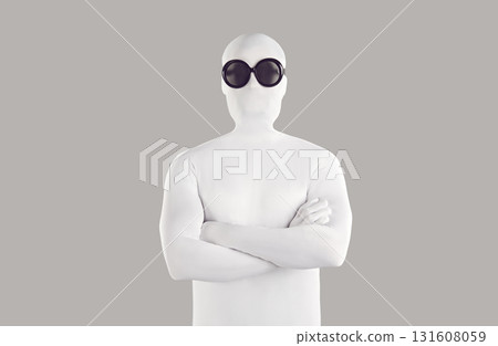 Portrait of person in white bodysuit costume and black sunglasses with folded arms 131608059