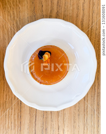 Elegant dessert tart with apricot glaze and edible flower on plate, top view. Fine dining, gourmet sweets, and patisserie presentation with tea. Elegant dessert tart with apricot glaze and edible flower on plate, top view. Fine dining, gourmet sweets, and patisserie presentation with tea. 131608091