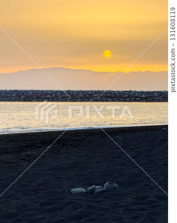 A Tenerife beach with black volcanic sand at sunset. 131608119