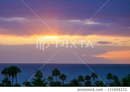 Purple Sunset Over La Gomera island. View from Tenerife with Dramatic Clouds and Silhouetted Palms Purple Sunset Over La Gomera island. View from Tenerife with Dramatic Clouds and Silhouetted Palms 131608152