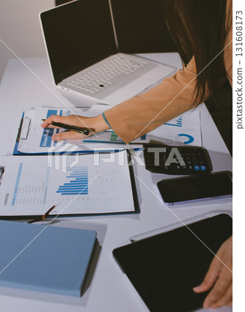 Close-up of businessman's hands making notes, mobiles, chart, desk, office 131608173