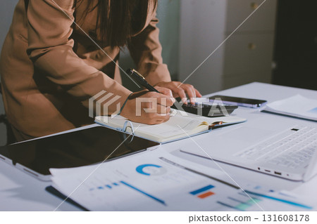 Close-up of businessman's hands making notes, mobiles, chart, desk, office Close-up of businessman's hands making notes, mobiles, chart, desk, office 131608178