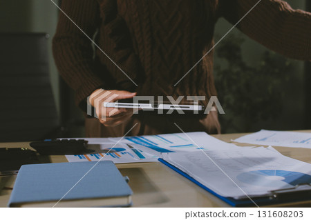 Close-up of businessman's hands making notes, mobiles, chart, desk, office 131608203