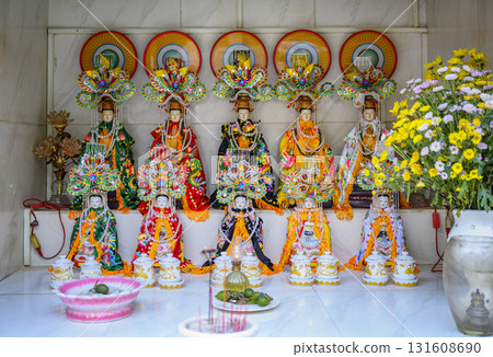 Buddhist sculptures decorated with bright clothes on a marble altar with flowers 131608690